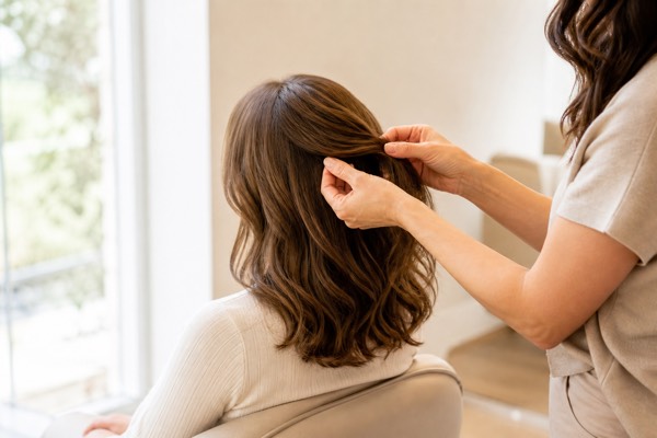 Blend and Style a Hair Topper woman gently styling a blended human hair topper with soft waves in natural window light
