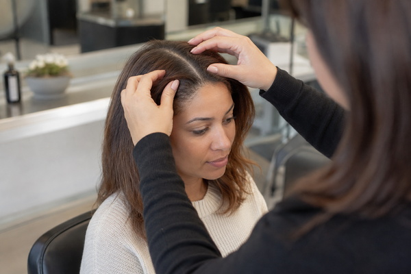 Close view of a woman with a natural hair part checking her scalp after a shower